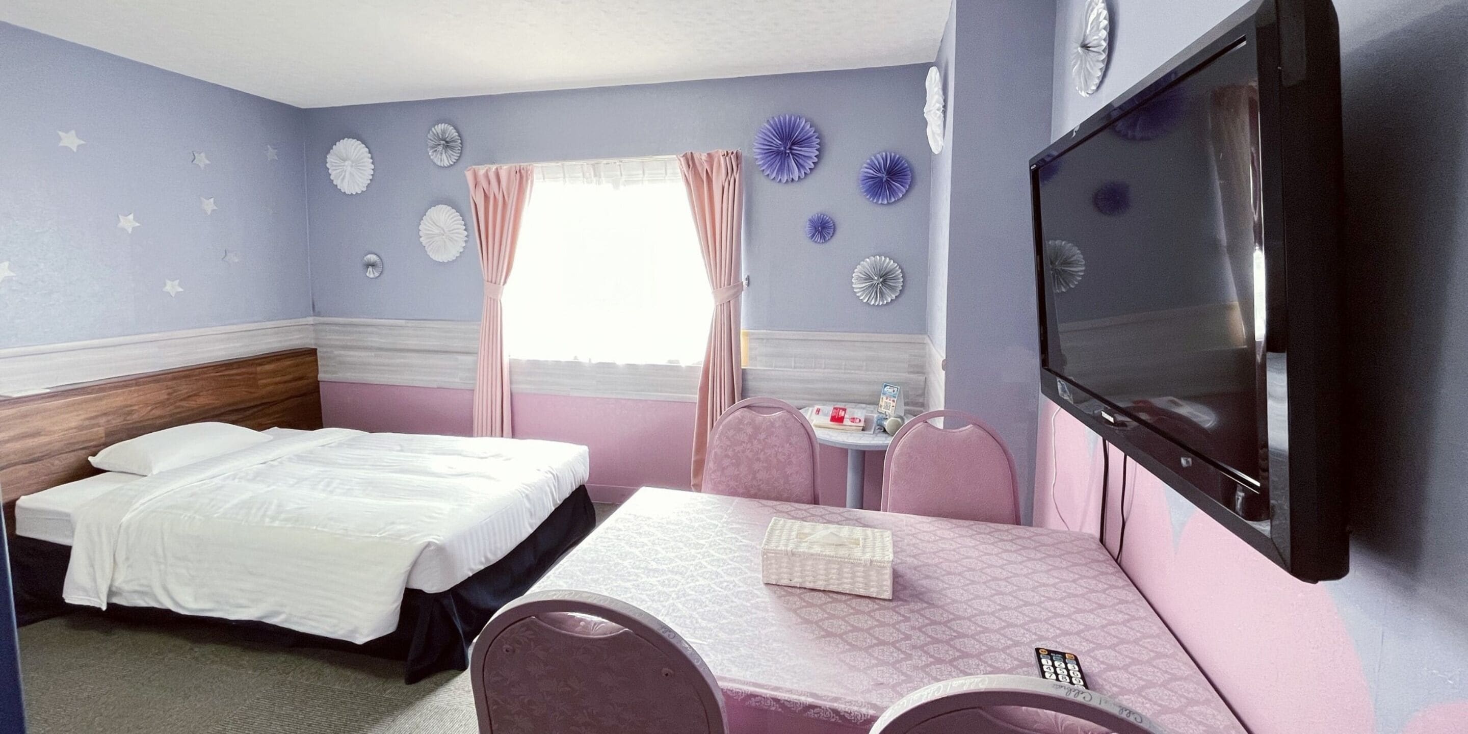 A bedroom with a bed, a desk, a chair, a TV, and decorative wall items.