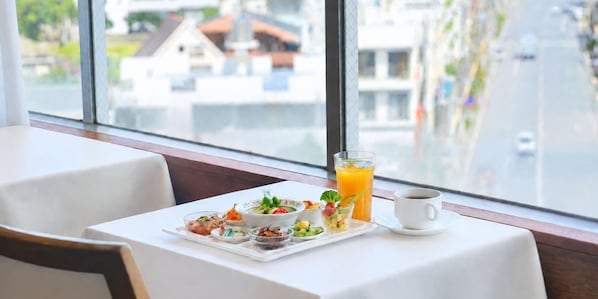 A breakfast setting with a table set for two, a glass of orange juice, a cup of coffee, and a variety of small dishes with food. - Hotel OROX (Naha)