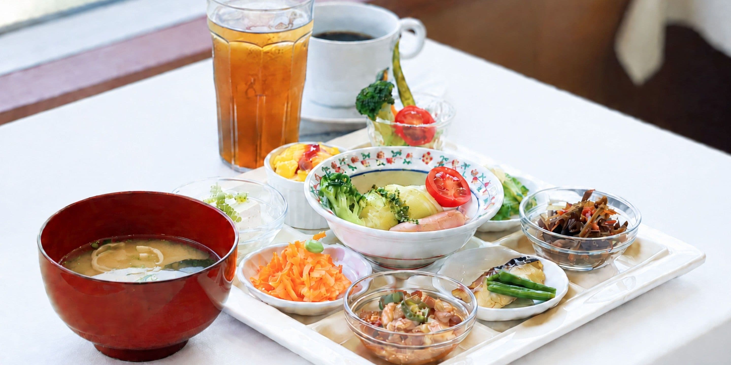 Una bandeja con diferentes platos, como sopa, verduras y una bebida.