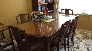 A dining table with chairs, a bottle, and a fruit bowl. - The Evergreen B&B (Braddon)