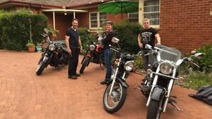 A brick house with a tiled roof, a green umbrella, and three motorcycles parked in front. - The Evergreen B&B (Braddon)