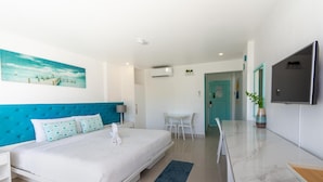 A modern hotel room with a bed, a TV, a desk, and a dining area. - Indila Boracay (Boracay Island)