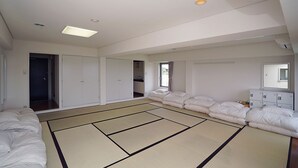 A room with tatami mats, a bed, a wardrobe, and a mirror.