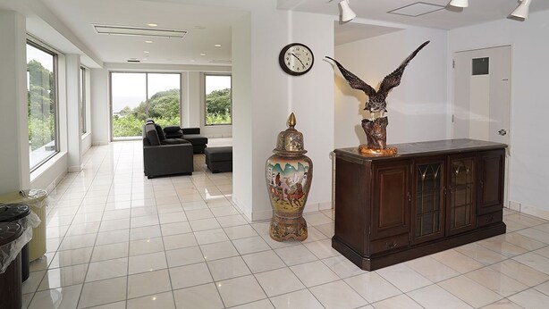 A spacious living area with a large window, a decorative vase, and a cabinet.
