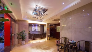 Een hotel lobby met een receptiebalie, een zithoek en een grote kroonluchter.