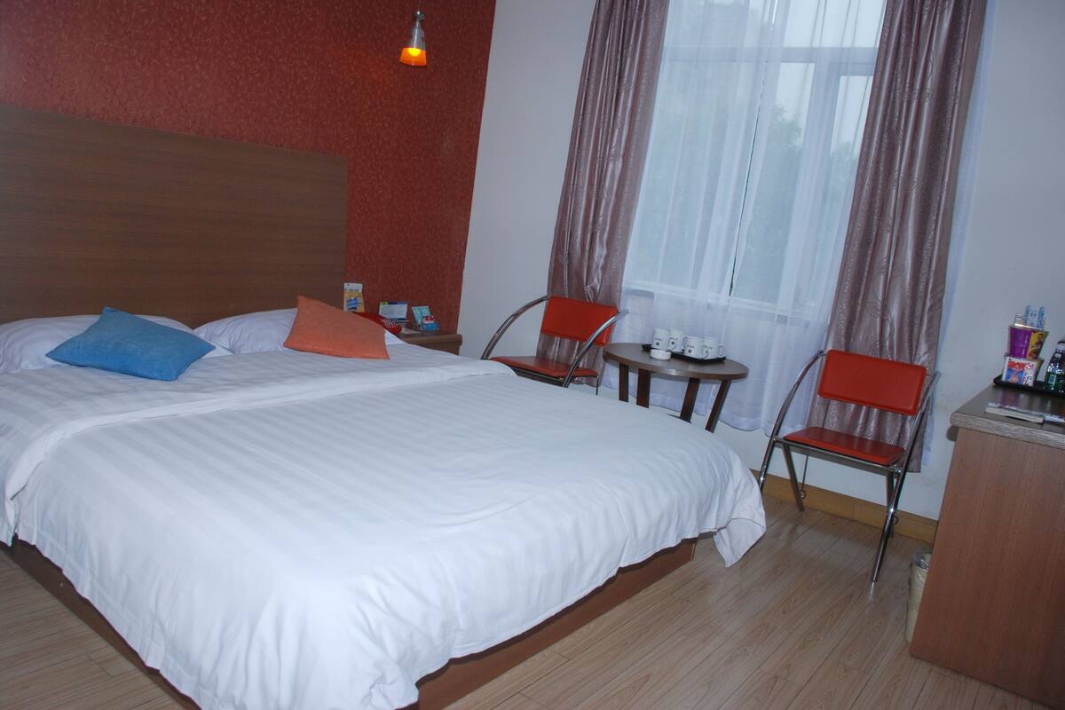 Ein Hotelzimmer mit einem großen Bett, zwei Stühlen, einem kleinen Tisch und einem Schreibtisch.