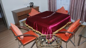 A dining area with a table covered by a red velvet tablecloth, surrounded by orange chairs with metal frames. - Ane 158 Hotel Bazhong Branch (Bazhong)