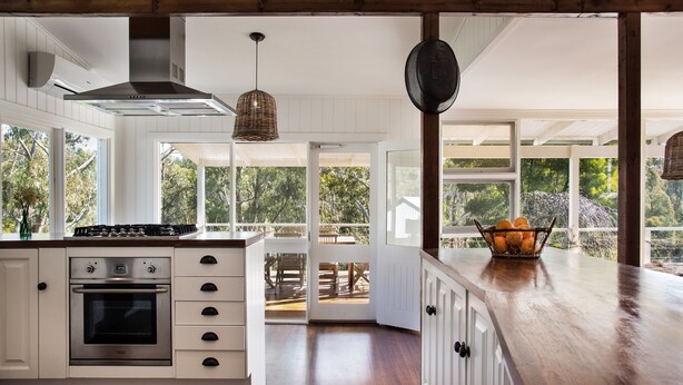 Una cocina moderna con armarios blancos, un horno de acero inoxidable y una encimera de madera.