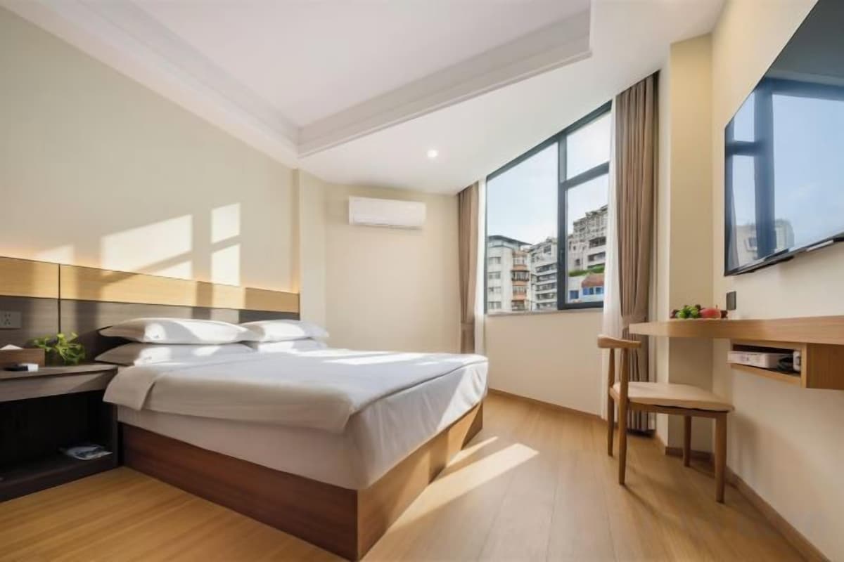 A modern bedroom with a bed, bedside table, and a large window.