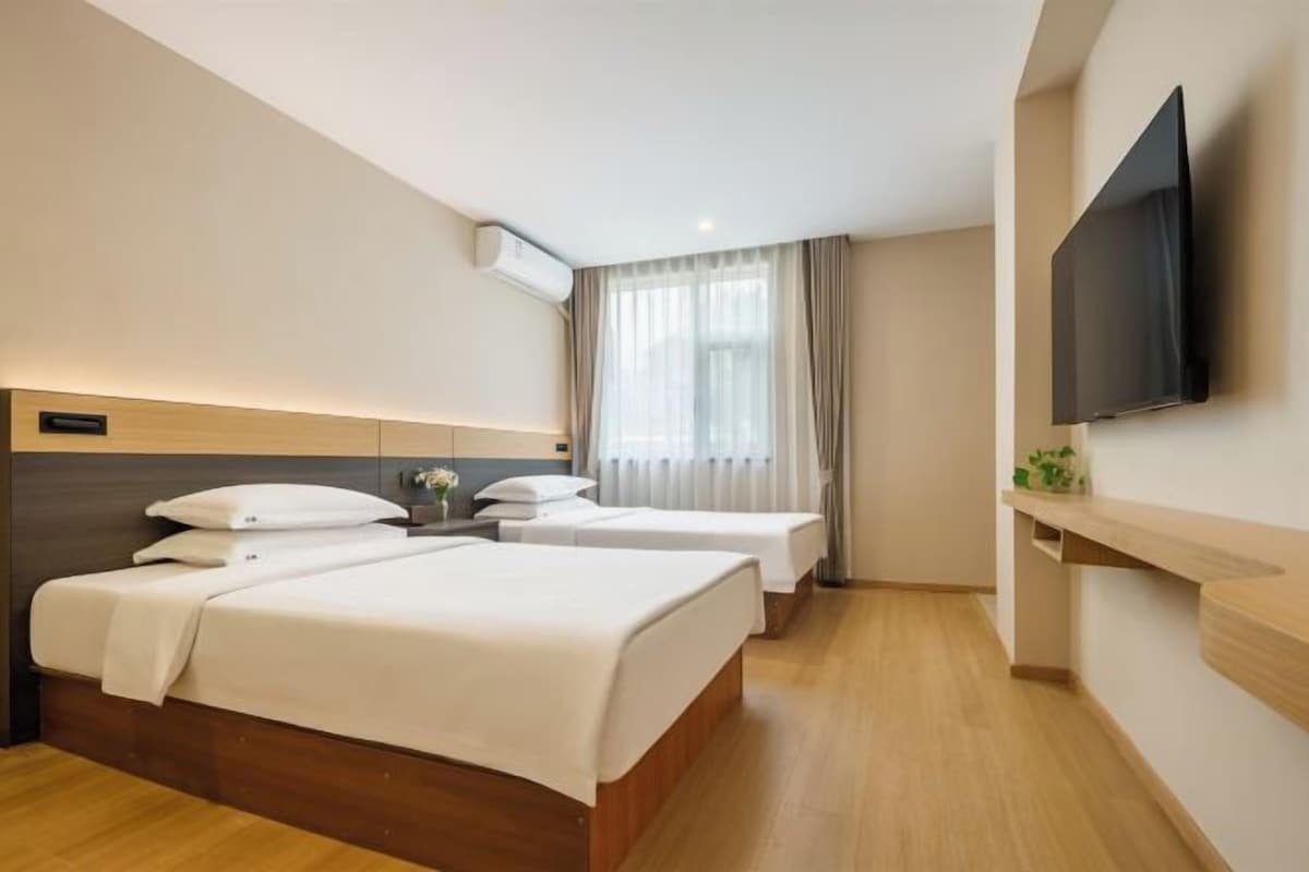 A hotel room with two beds, a television, and a window with curtains.