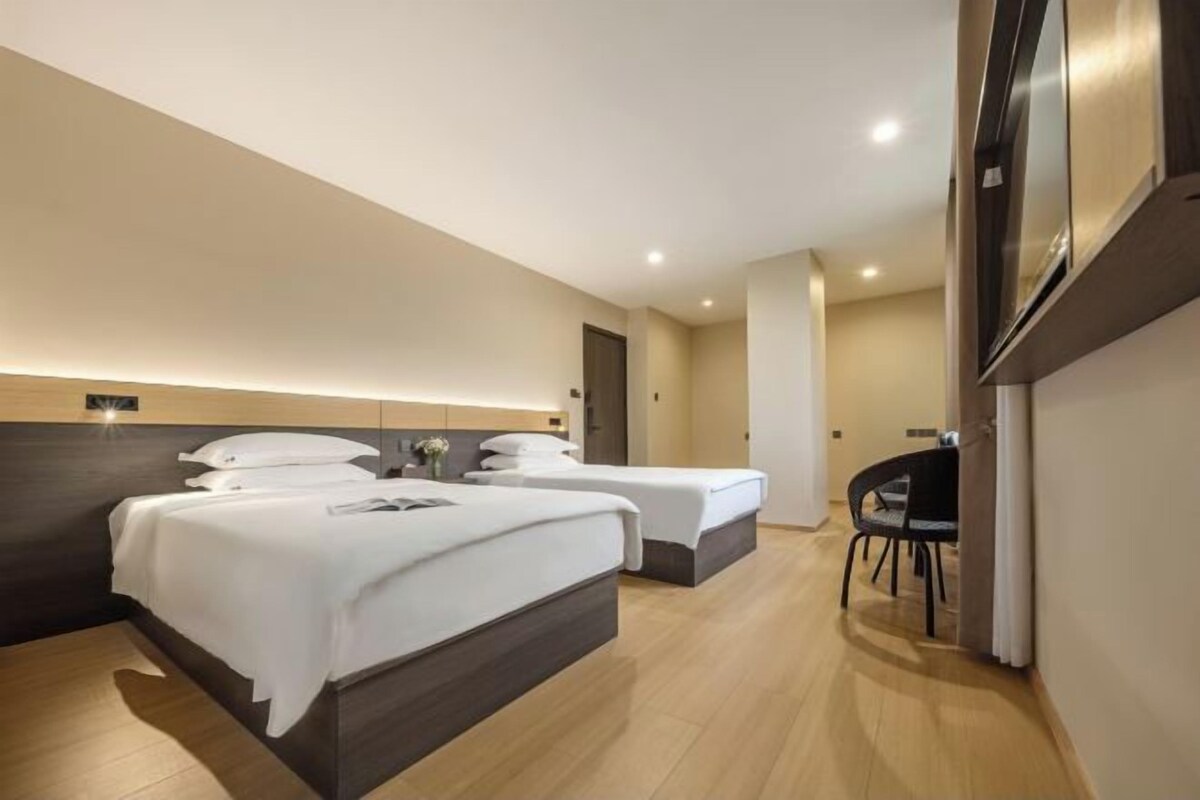 A hotel room with two beds, a desk, and a chair.