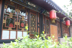 Un edificio tradicional con puertas y ventanas de madera ornamentada, farolillos rojos y techo de tejas.