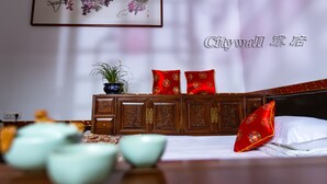 A traditional room with a wooden headboard, a framed artwork on the wall, and a bed with red pillows.