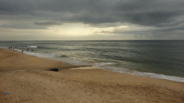 Une plage avec un rivage sablonneux et un ciel nuageux.