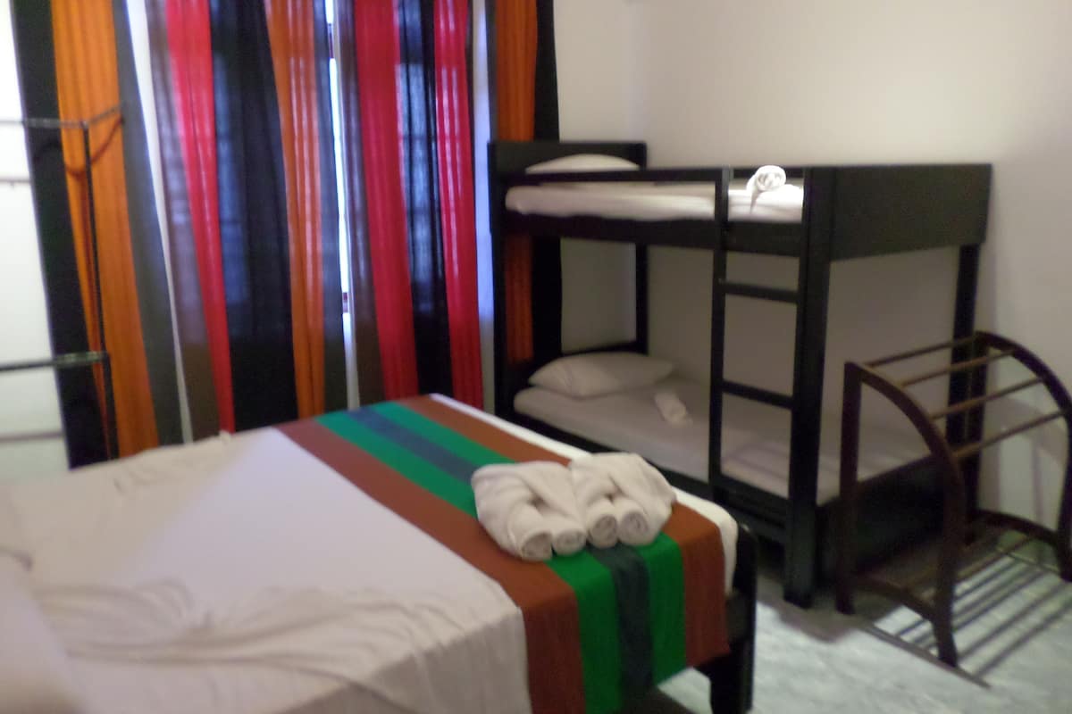 A bunk bed room with a striped bedspread, a chair, and colorful curtains.