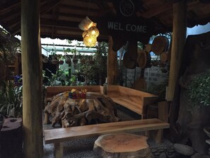 Un banco de madera de diseño rústico, rodeado de plantas en macetas y una lámpara colgante.