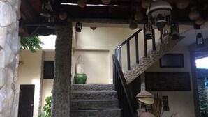 A staircase with stone steps and a metal railing, leading to a landing with a green vase and a wall-mounted light fixture.