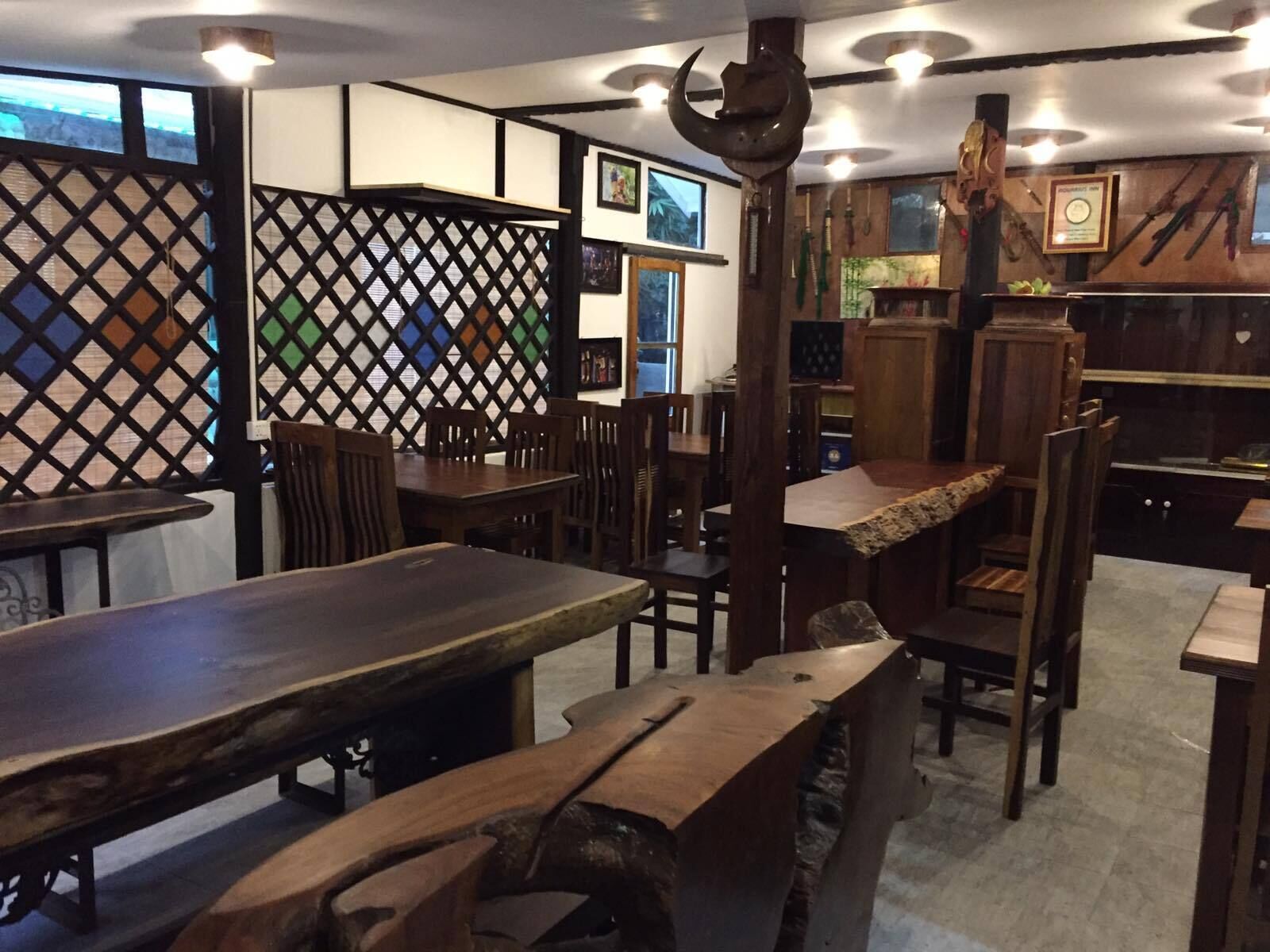A restaurant interior with wooden tables and chairs, a lattice partition, and various wall decorations.