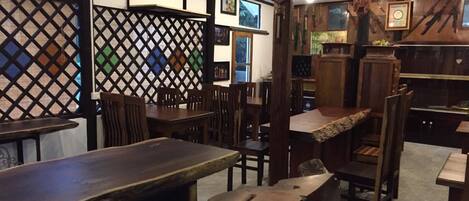 A restaurant interior with wooden tables and chairs, a lattice partition, and various wall decorations.
