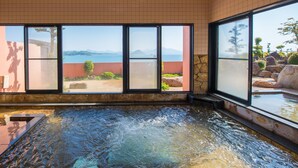 A hot tub with a view of the sea and mountains through large windows. - Hotel Shouryuen Kaisei (Kamiamakusa)