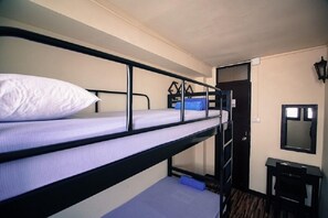 Une chambre avec un lit superposé, une porte, une petite table et un miroir au mur.