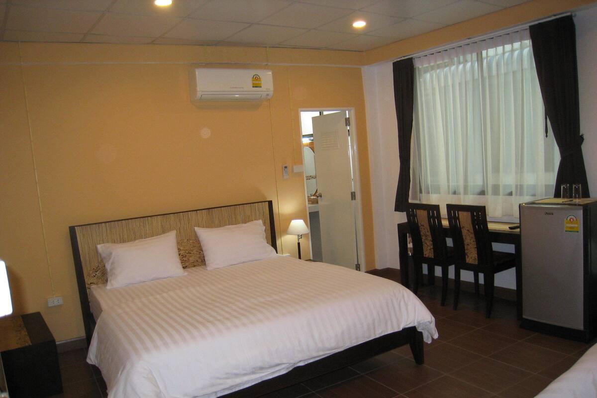 Une chambre d’hôtel équipée d’un lit, d’un bureau, de chaises, d’un réfrigérateur et d’un appareil de climatisation.