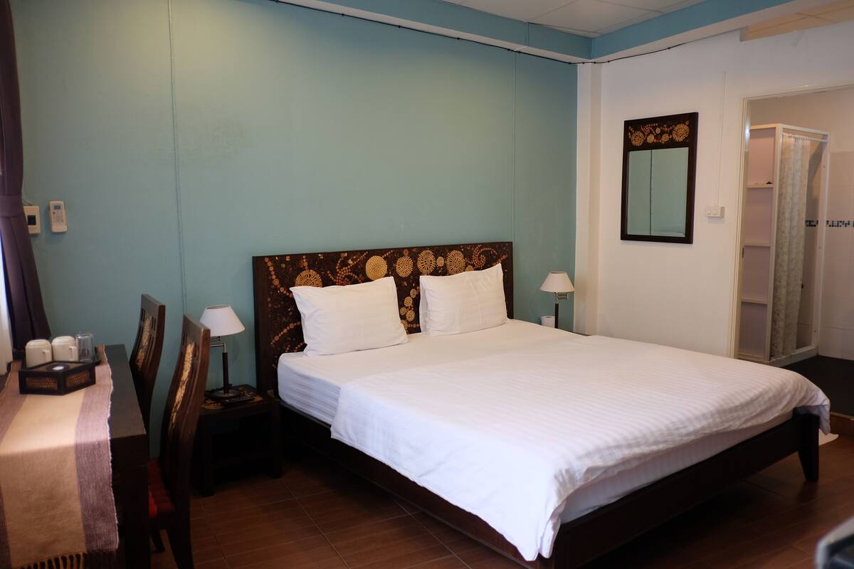 Une chambre d’hôtel bien aménagée, avec un grand lit, des tables de chevet, un bureau et une armoire.