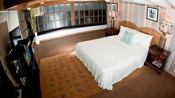Une chambre à coucher avec un grand lit, une fenêtre avec des stores, une table de chevet avec une lampe et un tapis décoratif.