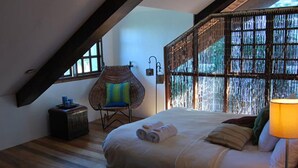 Une chambre avec un grand lit, une chaise, un radiateur et une fenêtre donnant sur un beau paysage.