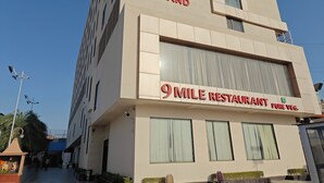 Un edificio moderno con la señalización 'Chandra Grand' y '9 Mile Restaurant Pure Veg'.