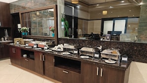 Mostrador de buffet con diferentes alimentos y un espejo grande colgando encima.