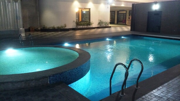 Una piscina interior con hidromasaje, suelo de baldosas y pared azulejada.