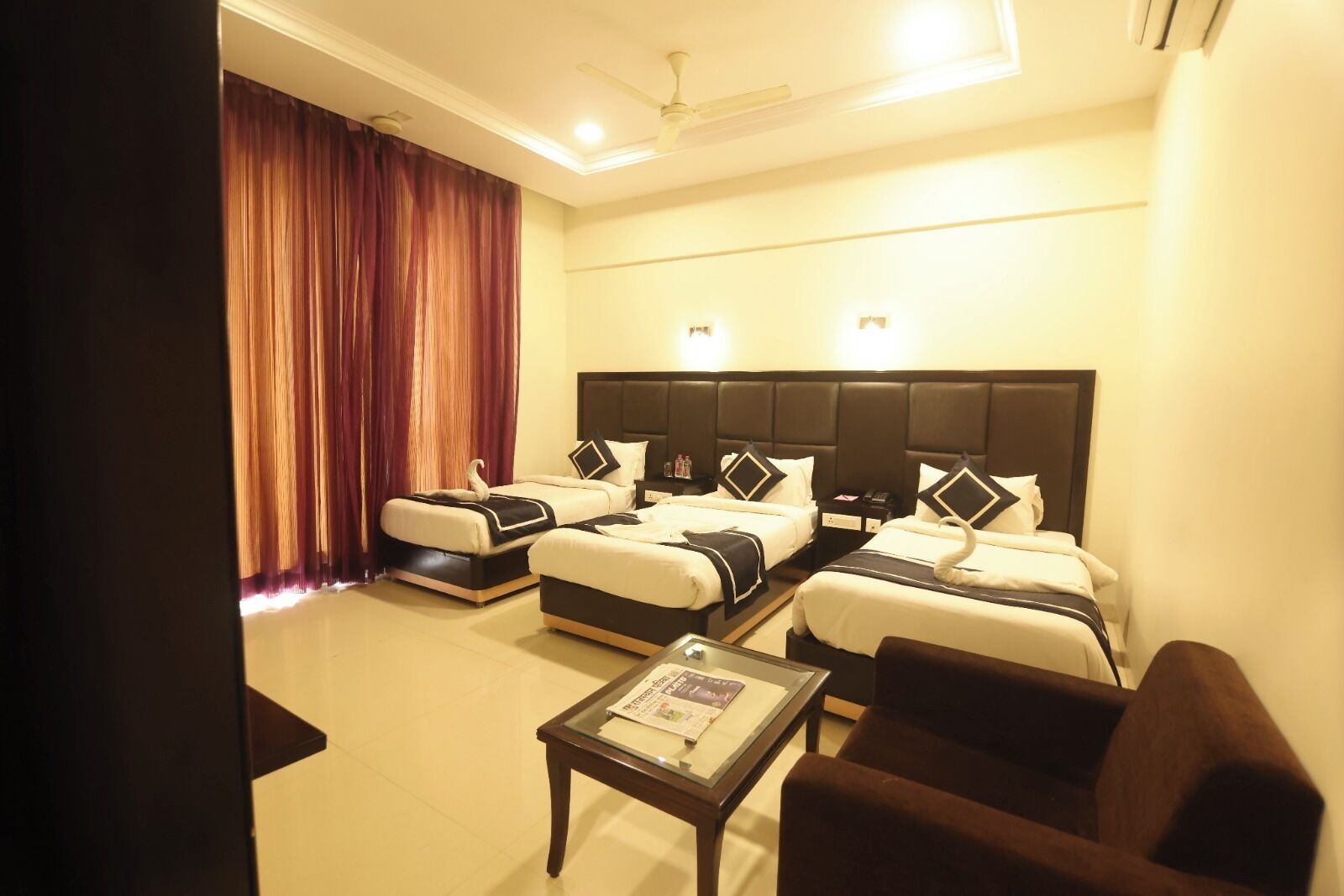 A hotel room with two beds, a small table, and a chair.