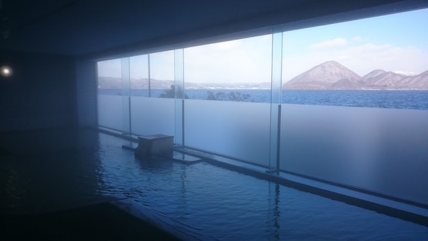 Una habitación con un amplio ventanal con vistas a un cuerpo de agua y montañas.