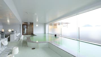Una piscina interior moderna con vistas a montañas, paredes de azulejos y una fila de lavamanos.