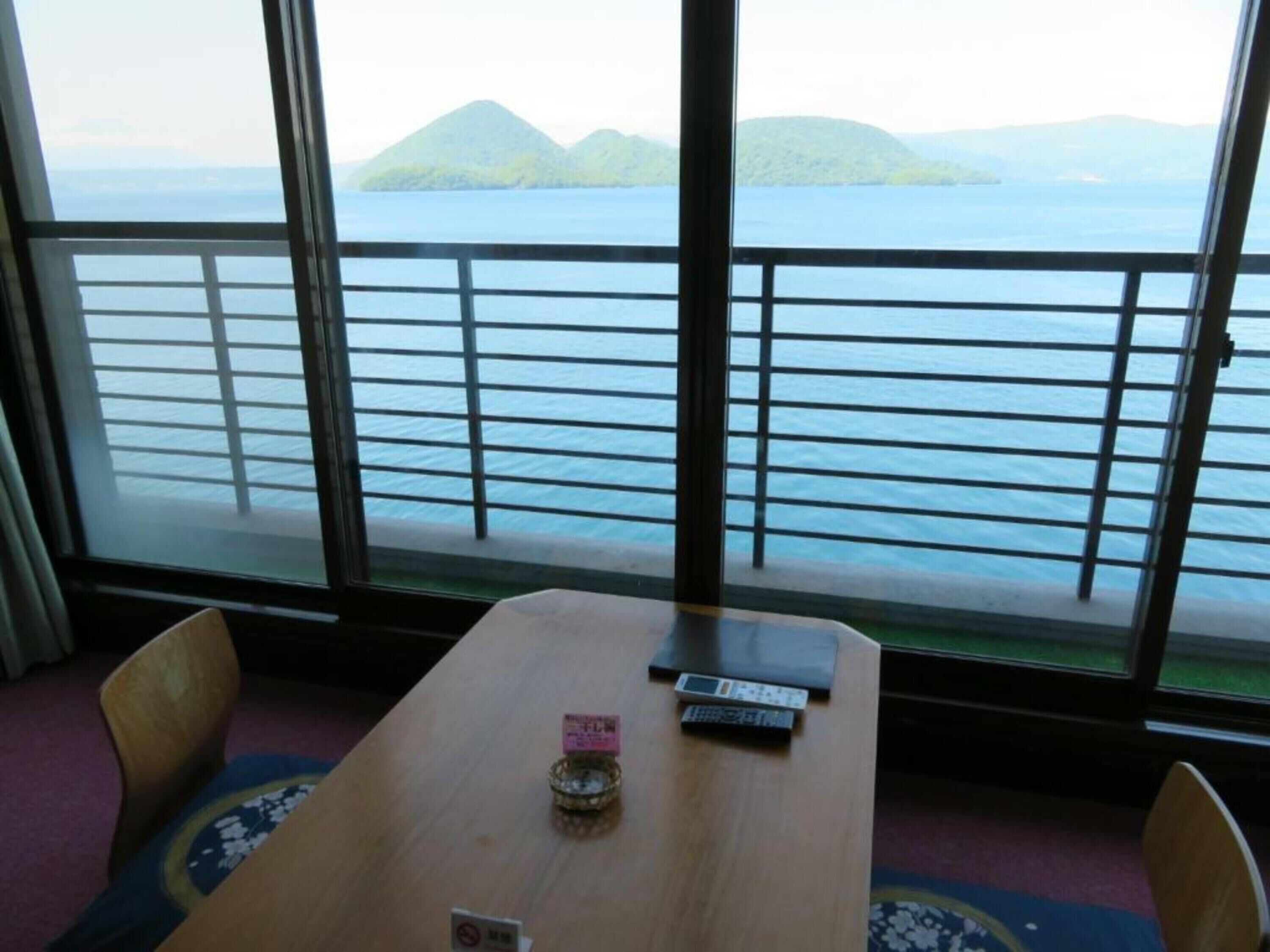 A room with a table, chairs, and a view of the sea and islands through large windows.