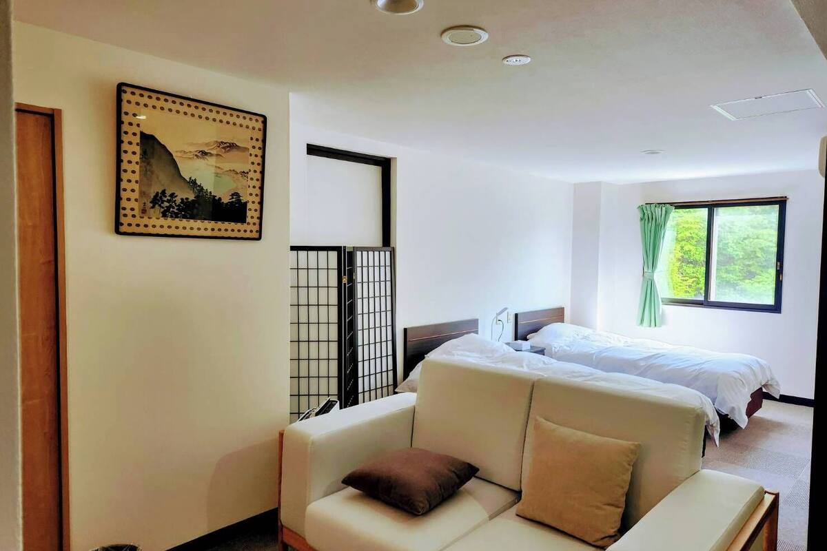 Ein Hotelzimmer mit Bett, einer Couch, einem Bild an der Wand und einem Fenster mit Vorhängen.