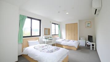A hotel room with two beds, a desk, a chair, a TV, and a wardrobe.