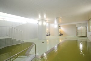 A swimming pool area with tiled walls, a staircase, and a glass door leading to another room.