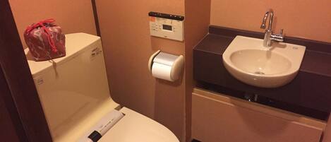 A small bathroom with a toilet, a paper towel dispenser, and a sink.