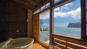Una cabaña de madera con un ventanal grande que da a un cuerpo de agua y una isla rocosa.