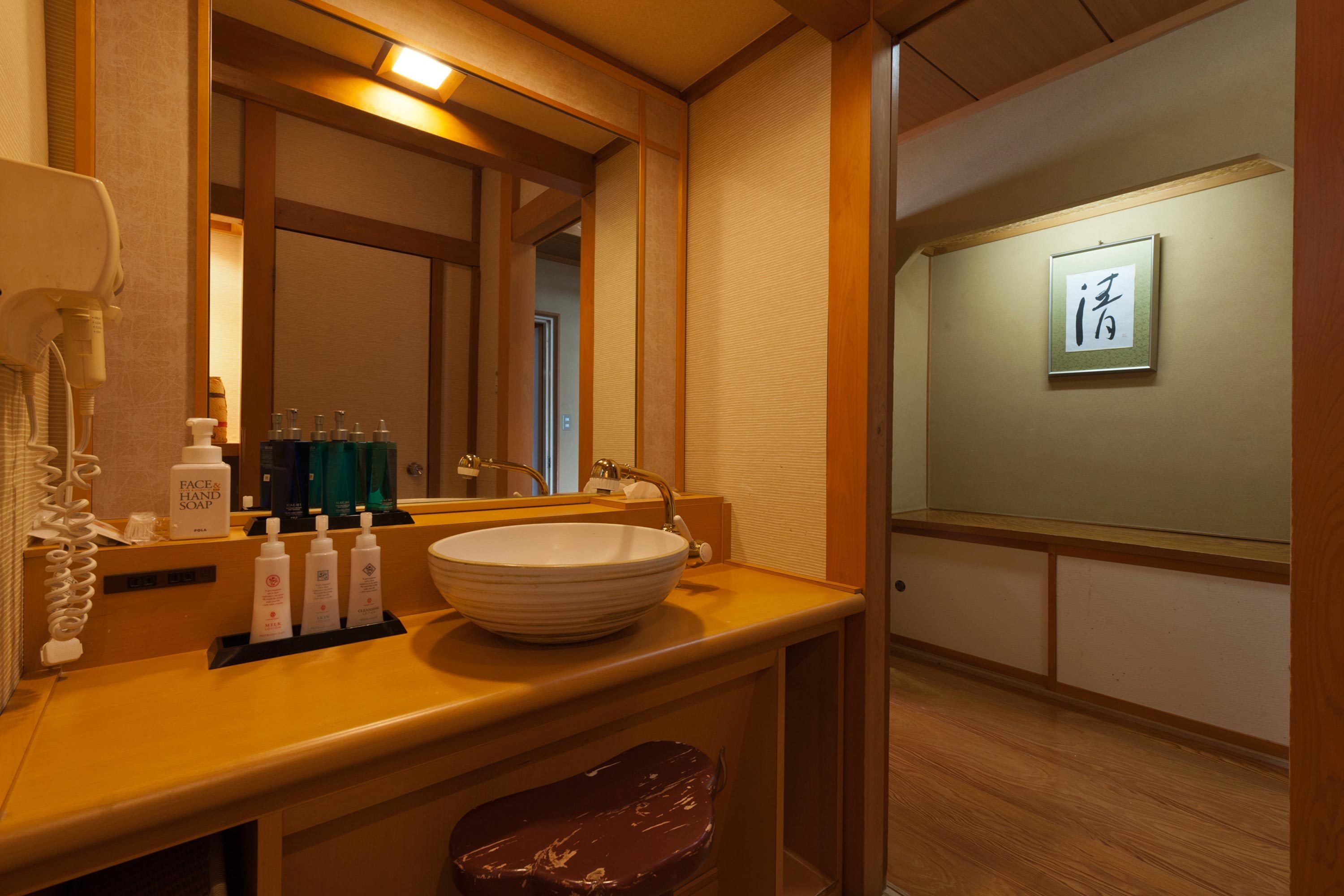 A hotel bathroom with a large mirror, a sink, and toiletries.