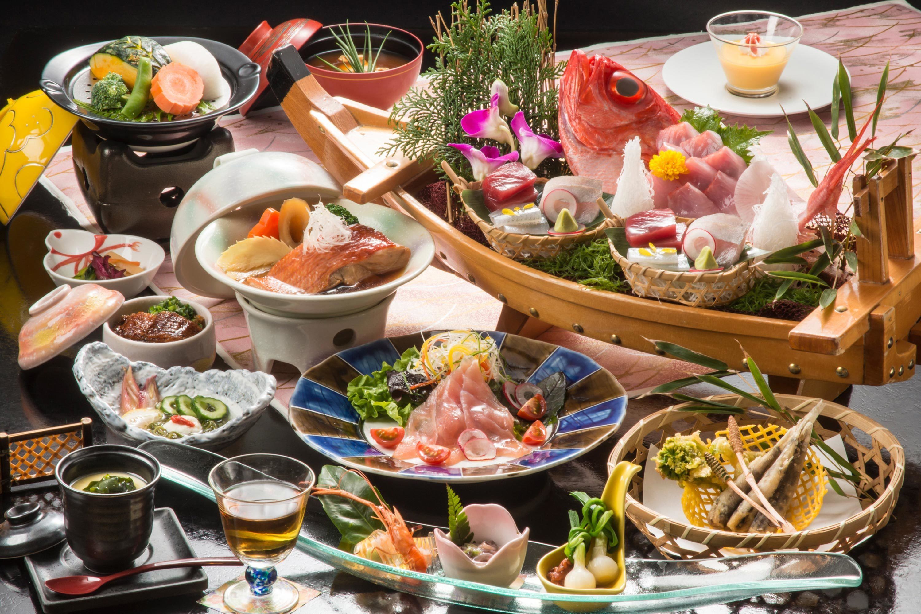 A variety of dishes and drinks on a table, including sushi, sashimi, and a bowl of soup.