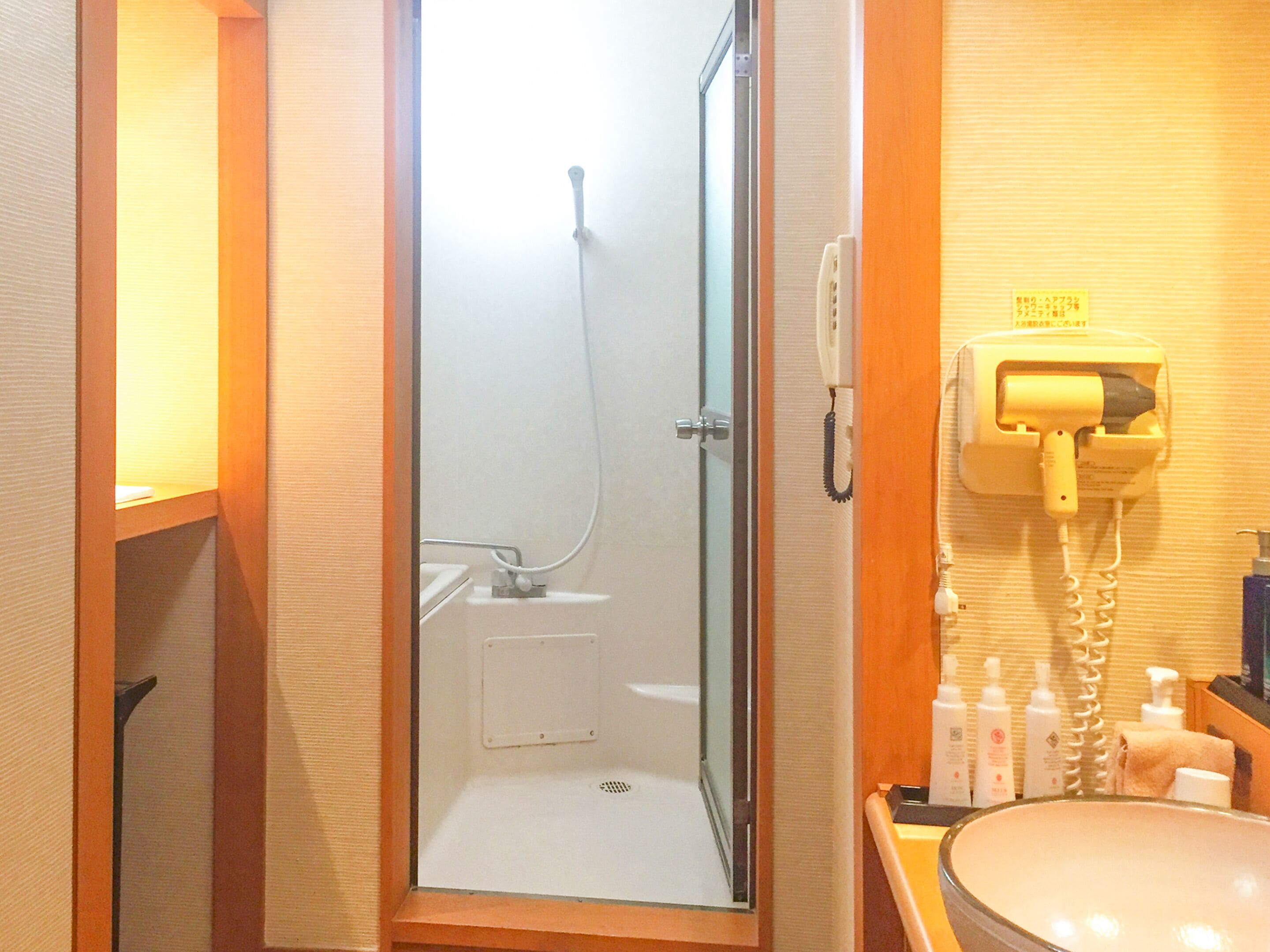 Une salle de bain d’hôtel avec une douche à parois de verre, un lavabo et un téléphone.