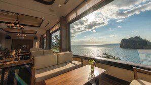 Un interior moderno con un amplio ventanal que ofrece vistas al mar y un acantilado.