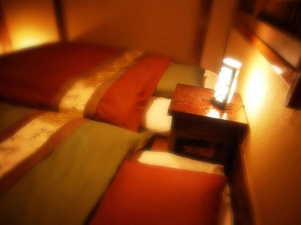 Una habitación tenuemente iluminada con una cama y una mesita de noche.