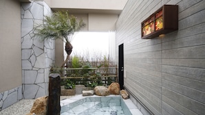 A spa area with a hot tub, stone walls, and a wooden wall with a decorative panel. - Hotel Dormy Inn Miyazaki Natural Hot Spring (Miyazaki)