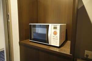 A microwave on a wooden countertop in a hotel room.