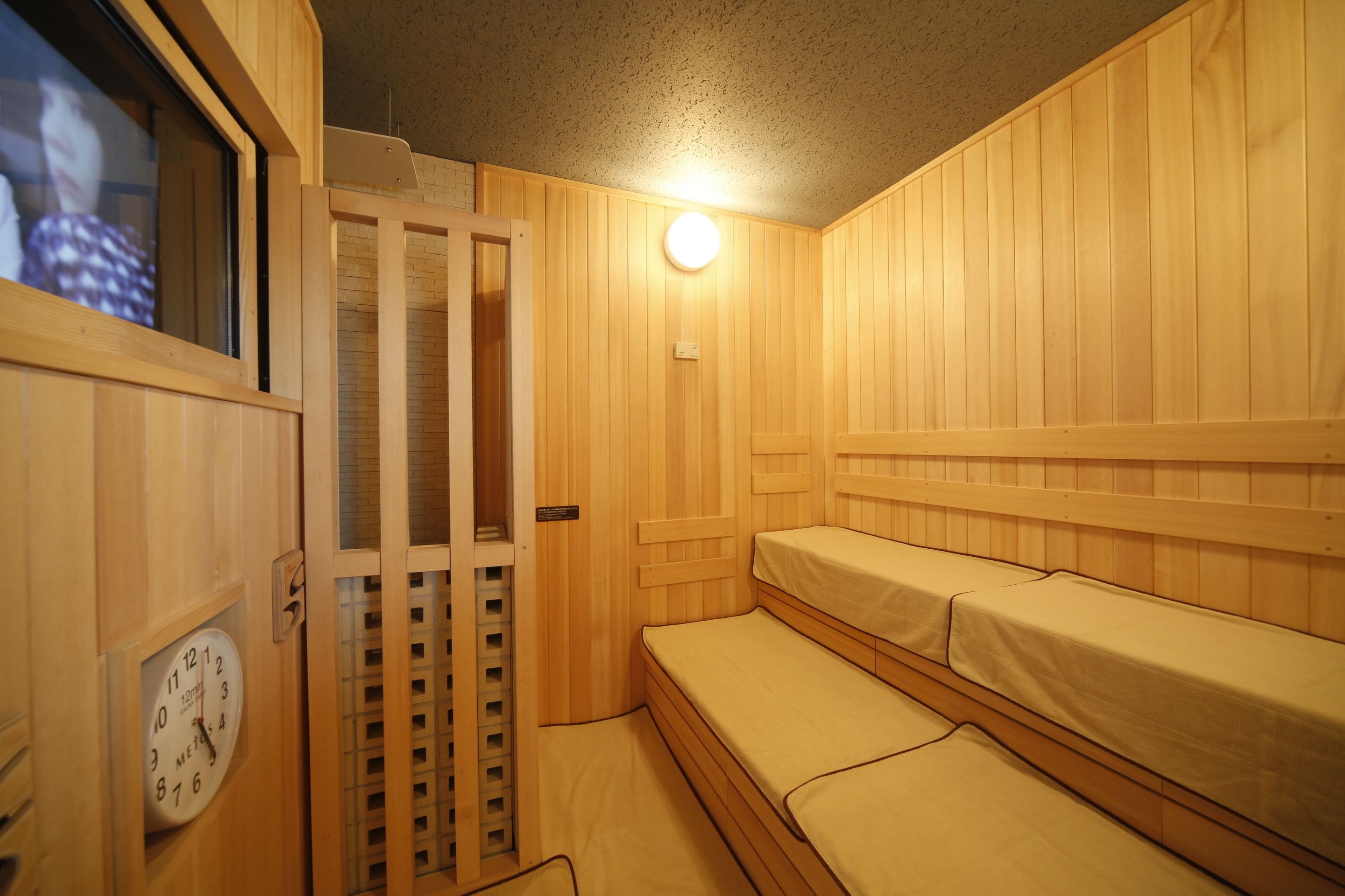A wooden room with bunk beds and a clock on the wall.