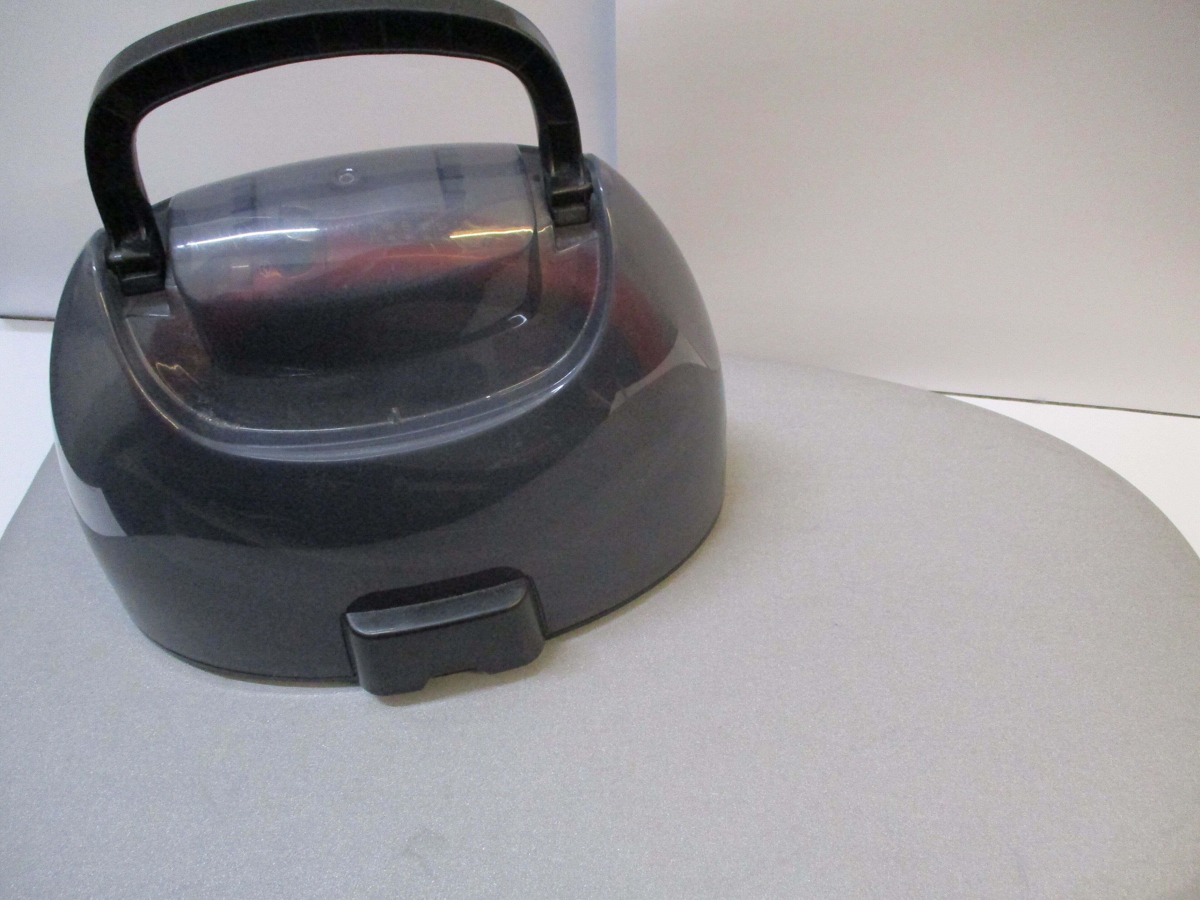 A black kettle with a handle and a lid on a flat surface.